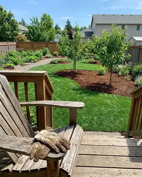 A maintained backyard with a healthy lawn, garden beds, and fresh mulch